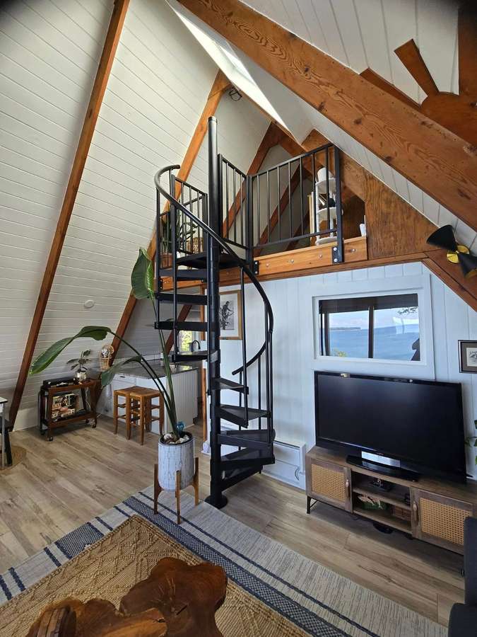 A-frame living room with a spiral staircase up to the loft