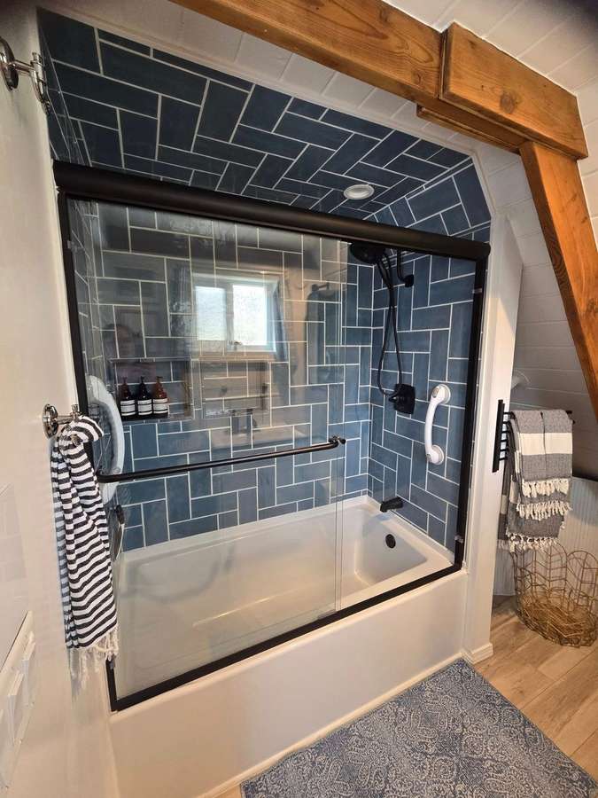 Shower in dark blue tile with a glass door