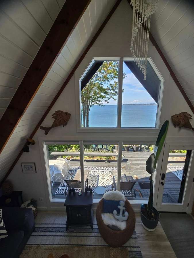 A-frame great room with a tall window looking toward the water